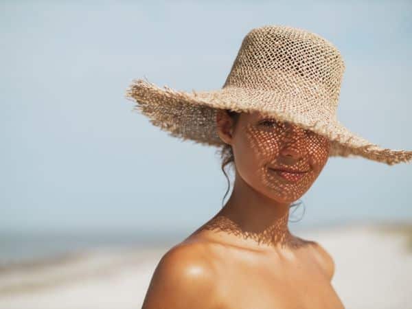 Linda mulher aproveitando o verão com a proteção adequada de um chapéu.